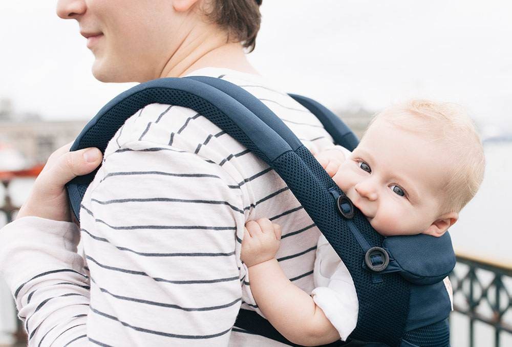 Scène de portage : bébé sécurisé dans un porte-bébé ergonomique