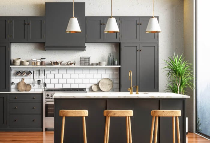 Cuisine ouverte au design moderne, façades gris anthracite, îlot central en marbre et suspensions dorées